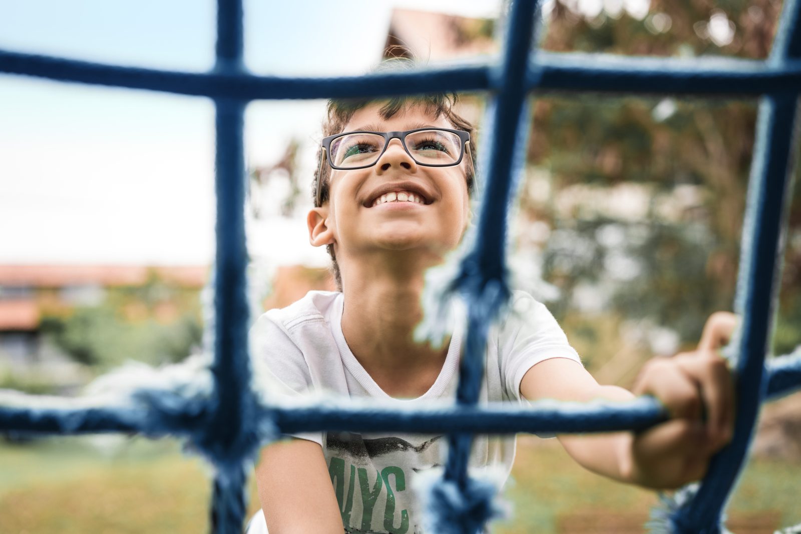 A boy in MiYOSMART spectacles climbing on a playground frame