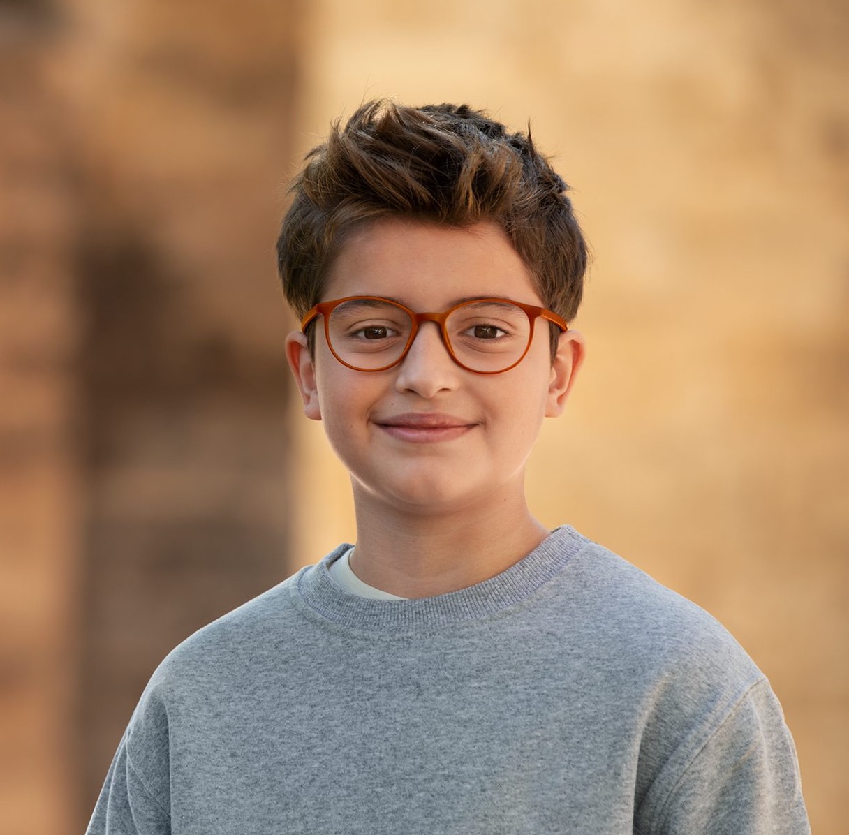 A smiling boy wearing MiYOSMART spectacles with orange frames