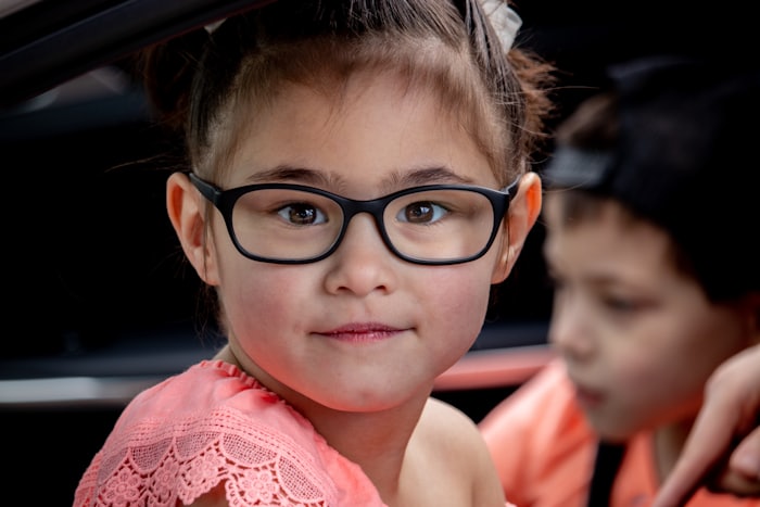 A girl in black-framed spectacles smiling after her eye check